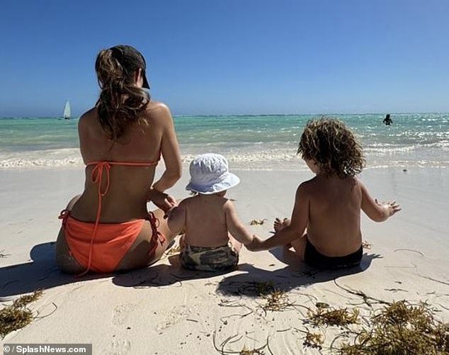 Lauryn Goodman slipped into a red bikini and posed with her two children Kairo and Kinara in a throwback snapshot on Friday