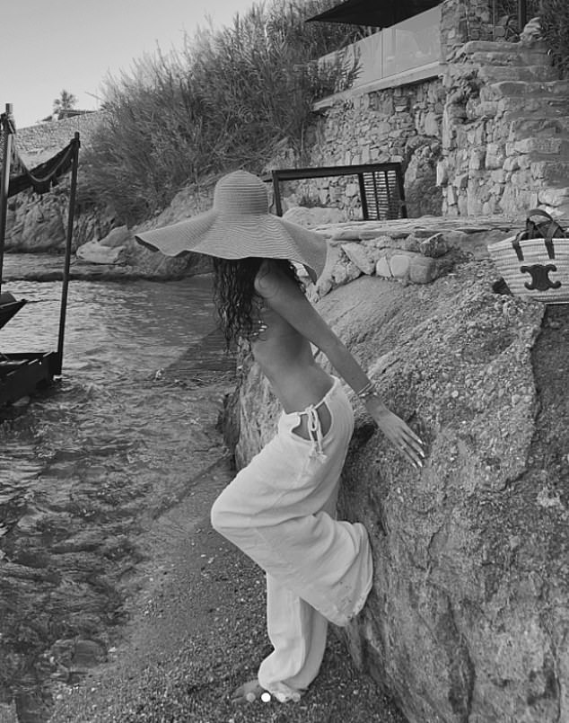 Standing by the sea, the blonde beauty was seen posing around the coast of Mykonos, wearing white linen trousers and a large beach hat