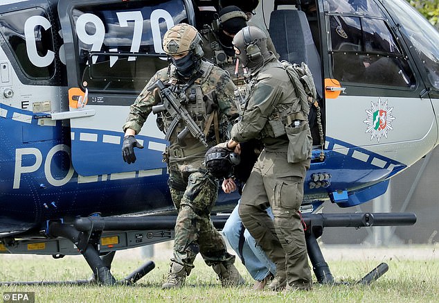 The suspect (pictured, center) was dragged today by federal police officers to his summons at the Federal Supreme Court (BGH) in Karlsruhe, Germany.