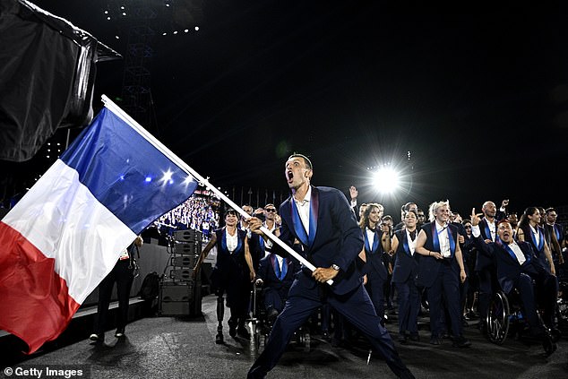 Triathlete Alexis Hanquinquant carries the French flag during the opening ceremony of the Paralympic Games