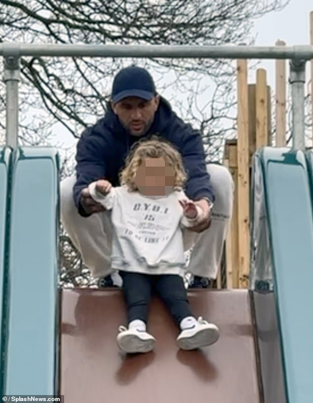 Kyle Waker supports the toddler as he goes down the slide