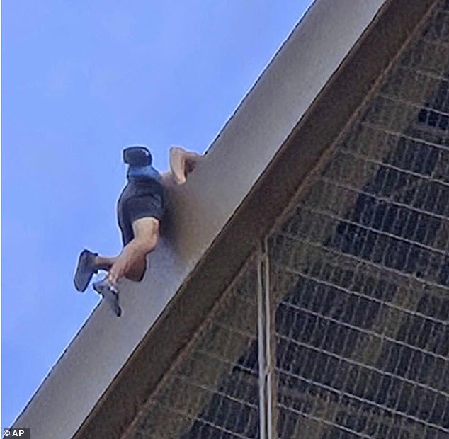 Davis is pictured hoisting himself over one of the iron beams on his way to the top of the Eiffel Tower