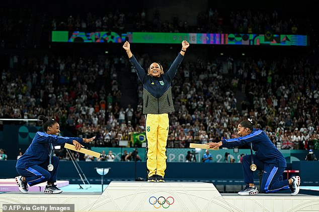 Simone Biles (L) and Jordan Chiles (R) bow to Rebeca Andrade after her victory in the floor final