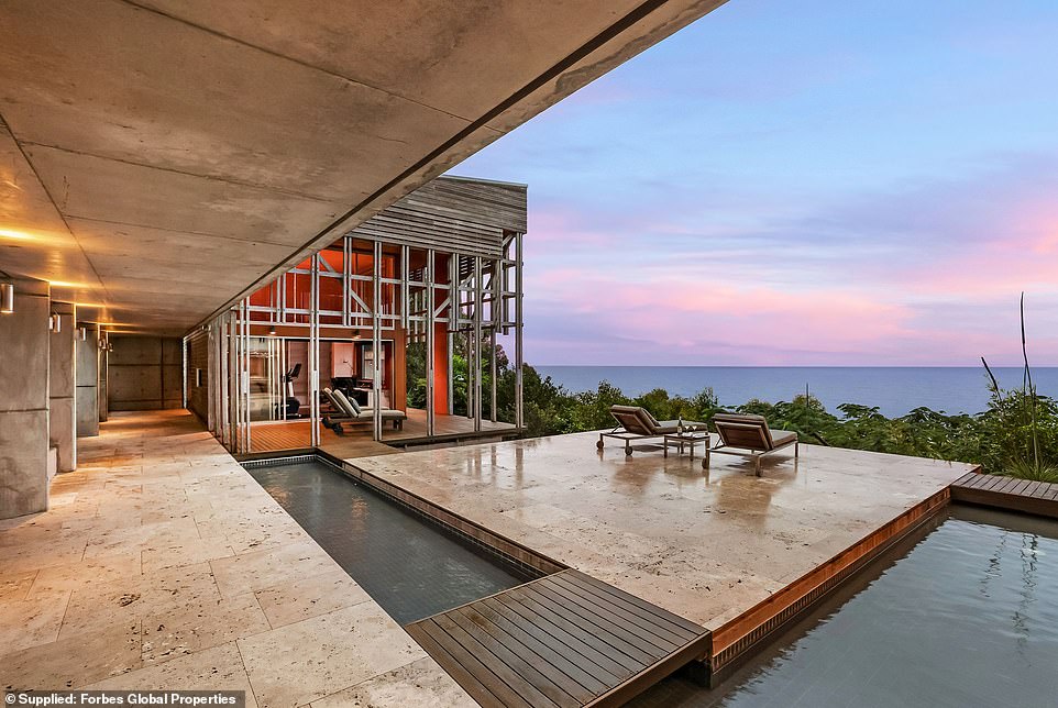 A stunning beach house carved into a cliff on the Southern Great Barrier Reef overlooks the sparkling azure waters of Honeymoon Bay