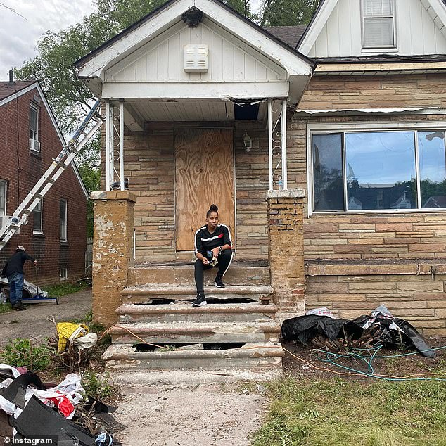 Chase C. Hunter poses on the steps outside her first Detroit home, which she purchased for $2,000 in June 2021