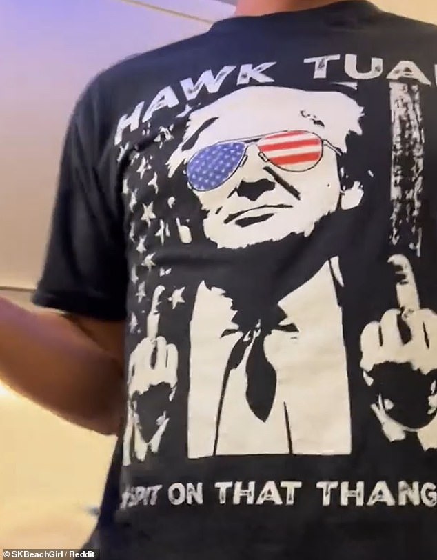 In the clip, the angry traveler is seen wearing a black T-shirt with an image of Trump wearing sunglasses with the American flag on them and holding the bird up in both hands