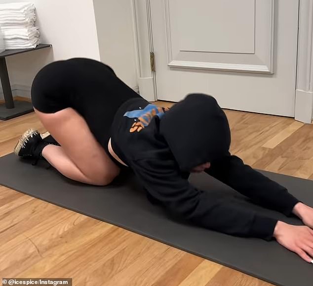 She wore black shorts and a hoodie as she stretched out on a yoga mat