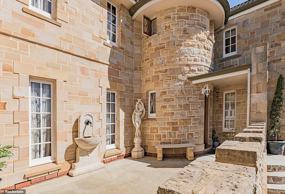 The grand entrance features a staircase leading to an inviting terrace to the gently arched Naytoah wood front door with statues and a fountain to the side