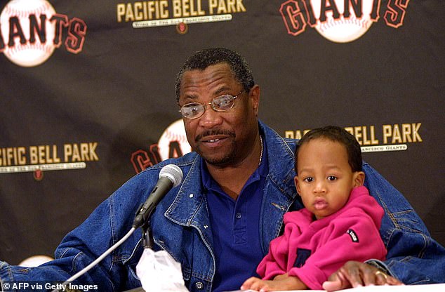 Giants manager Dusty Baker answers questions while holding his son Darren in 2000