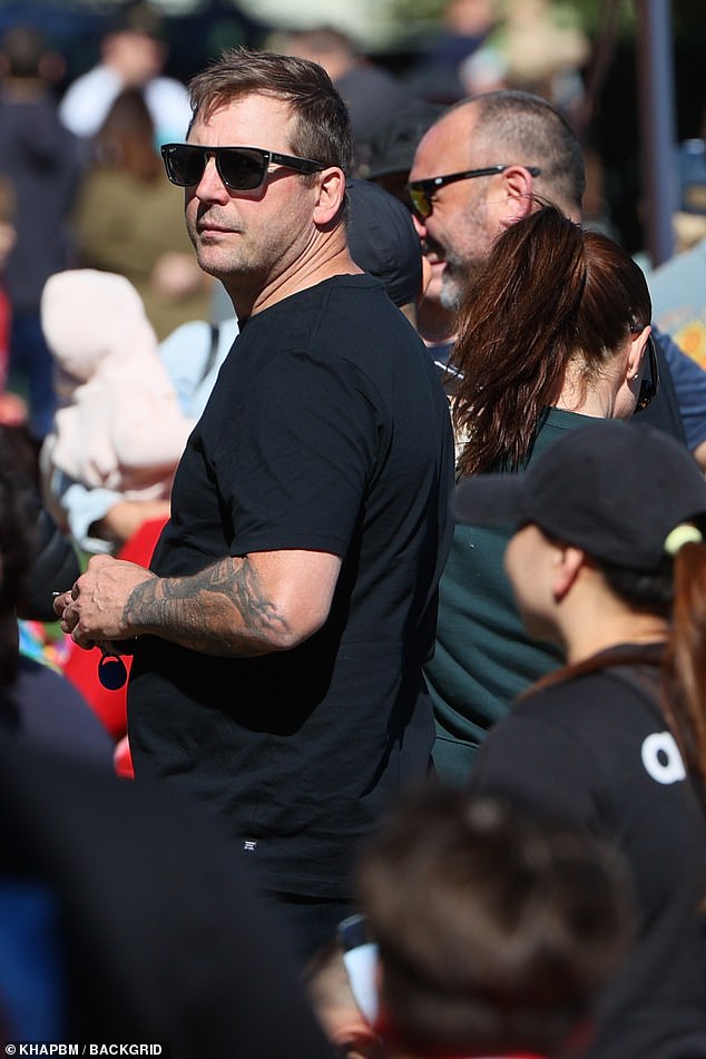 The father of one opted for a dark monochrome look with a black T-shirt and shorts, while shielding his eyes from the sun with a pair of sunglasses