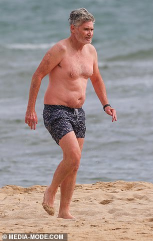 Hughesy looked relaxed as he went for a swim in navy and white patterned board shorts