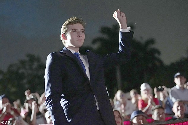 Trump holds his fist up as his father speaks during a campaign rally at Trump National Doral Miami, Tuesday, July 9, 2024, in Doral, Florida.