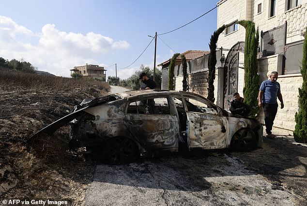 People check a burned-out car a day after an attack by Jewish settlers on the village of Jit near Nablus in the occupied West Bank, which left a 23-year-old man dead and others seriously wounded, on August 16, 2024