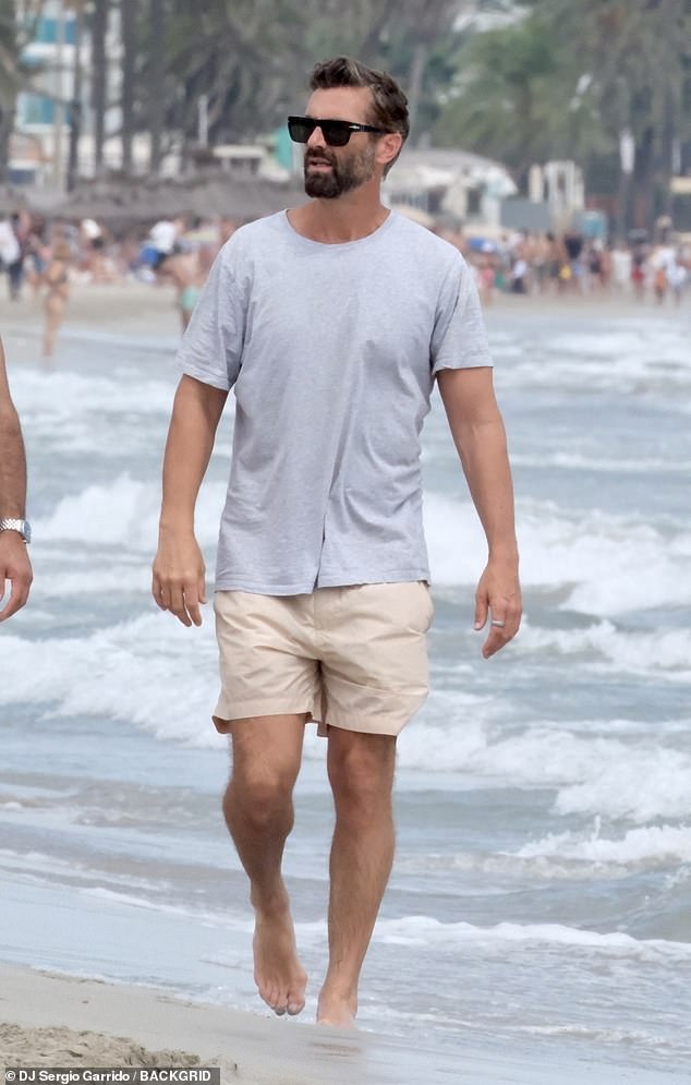 Meanwhile, Chris was spotted walking along the beach in dark sunglasses, a gray T-shirt and cream chino shorts