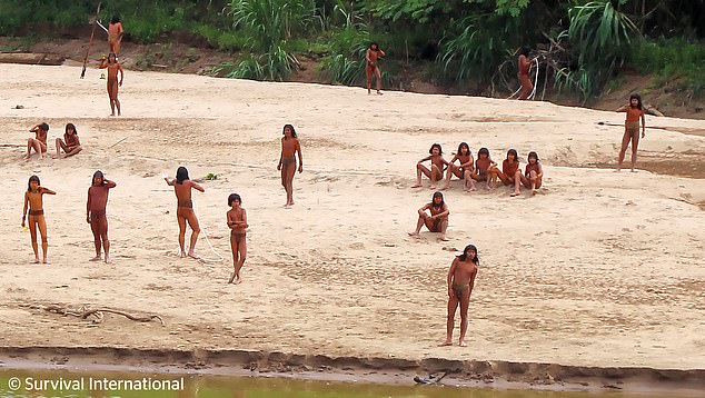 Tribesmen rest on the banks of the river while others carry spears and pause to talk (photo in June)