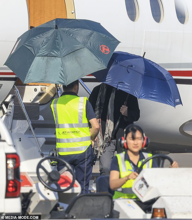 The Saturday Night Fever star, who is famous for his pilot's license, stepped off the plane carrying a giant blue umbrella and was greeted by ground staff, who appeared to be sponsored by Bunnings