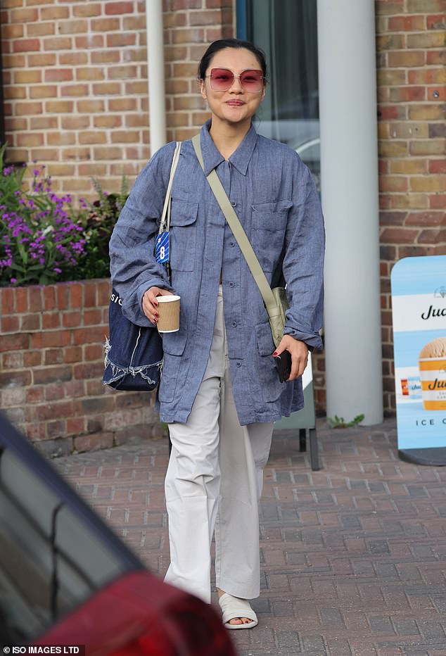 Nancy Xu looked chic in an oversized blue utility jacket and cream trousers as she held a coffee cup and her phone as she walked towards the candidates