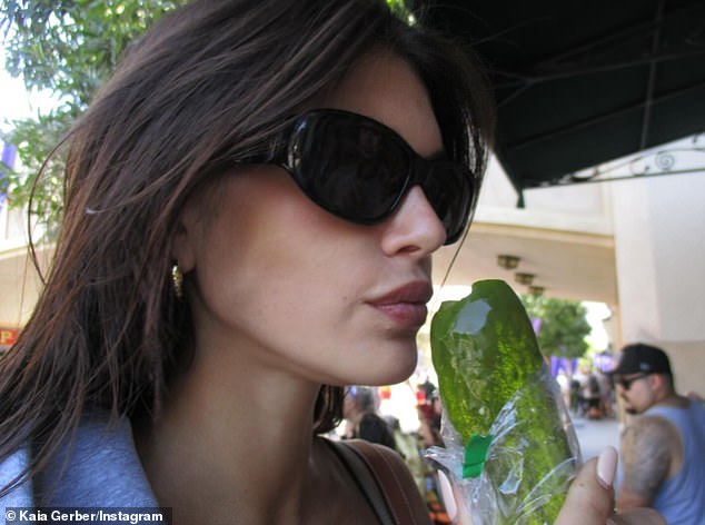 The Vogue cover girl wore black sunglasses as she nibbled on a pickle