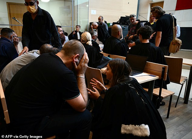 Some of the 50 co-defendants accused of rape speak to a lawyer at the courthouse in the case that shocked France on Monday