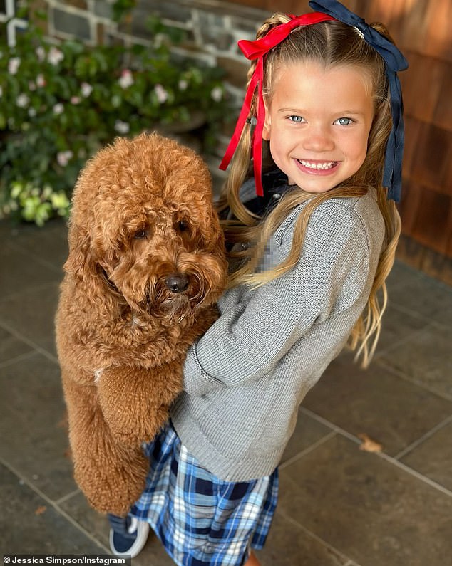 And little Birdie - who hugged doodle Penny Lane - flashed a smile in her two-tone hair bows, a gray cardigan over a black polo shirt, a blue plaid skirt and black Vans sneakers