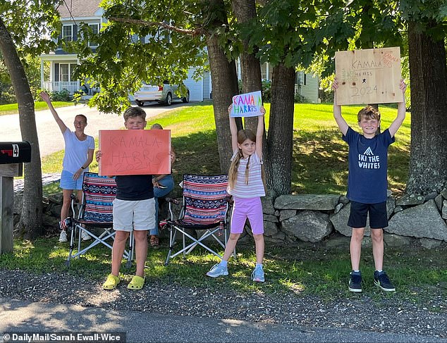 Children hold signs in support of Kamala Harris on the side of the road ahead of her visit to the state