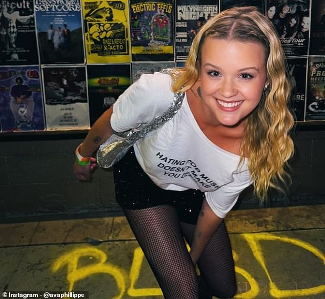 A smiling Ava pictured in June with her natural blonde hair. Her shirt reads: 'Hating pop music doesn't make you deep'