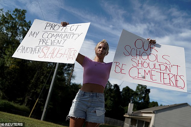 Student Gretchen Gierlach, 18, holds up banners after a shooting at Apalachee High School in Winder