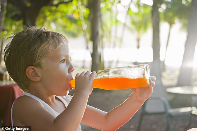 File photo of a young boy drinking an orange soda at a beach bar in the late afternoon light