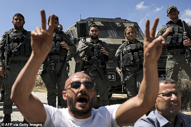 The Turkish-American citizen was a volunteer with the Faz3a campaign, which works with Palestinian farmers protesting against Israeli settlements. Pictured: Protesters sit in front of Israeli border guards during an earlier protest vigil