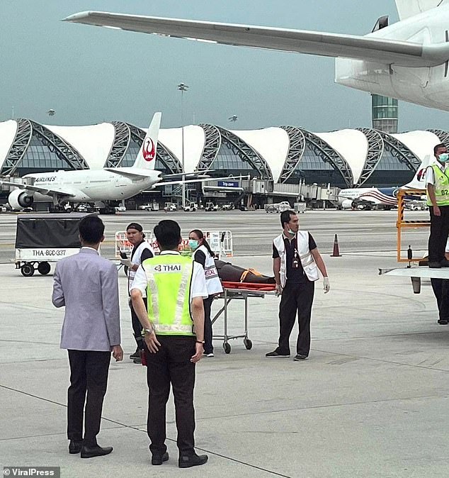 On May 20, a person is carried out of a plane on a stretcher in Bangkok