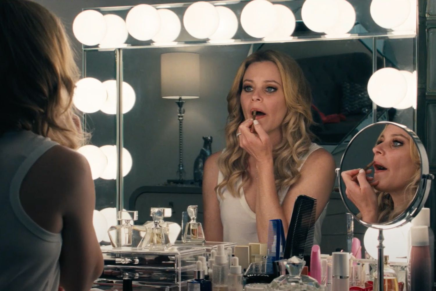 Elizabeth Banks applies lipstick in the mirror in Skincare.