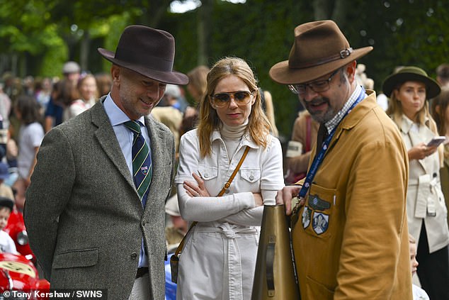 Christian put on a dapper display in a gray tweed blazer teamed with cream trousers, a blue skirt and a brown fedora hat to top things off