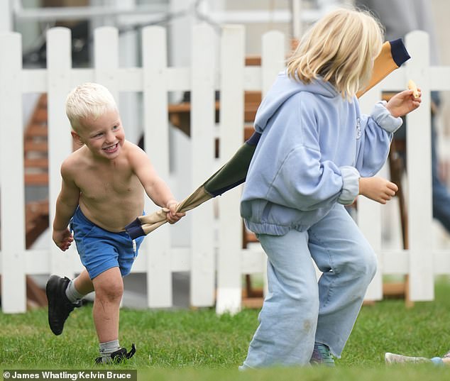 Lucas Tindall puts on his sister's jacket as they run through the grass