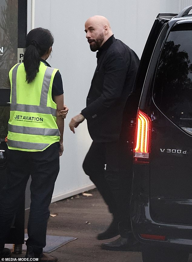 Arriving at the airport at the end of their visit, John looked dapper in a black shirt and blazer, which he paired with matching trousers