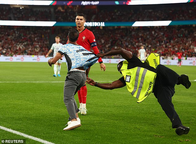 A steward desperately holds the intruder who has come within metres of Ronaldo