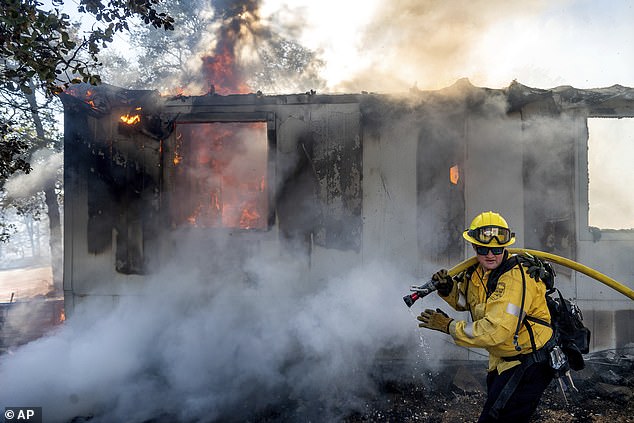 Firefighter Gus Laws extinguishes flames from a home as the Boyles Fire rages in Clearlake, California, on Sunday, September 8.