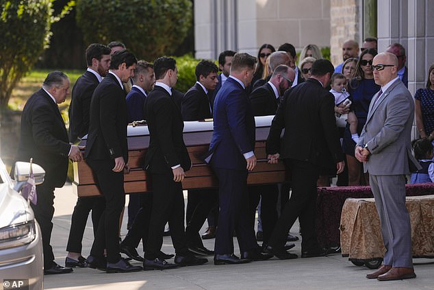 A group of loved ones carry John's casket into the church on Monday