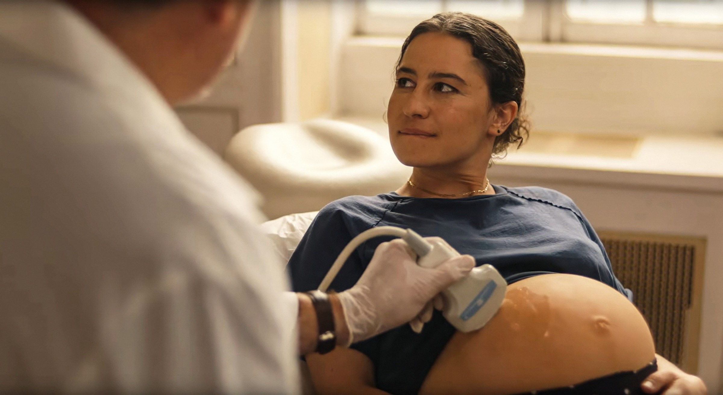 Ilana Glazer as Eden, a pregnant woman sitting and having an ultrasound