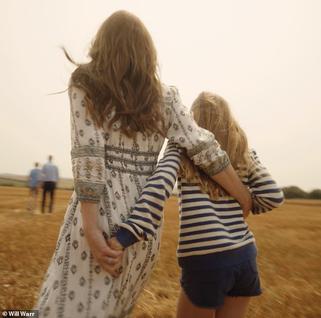 Catherine and Princess Charlotte link arms as they walk through a field