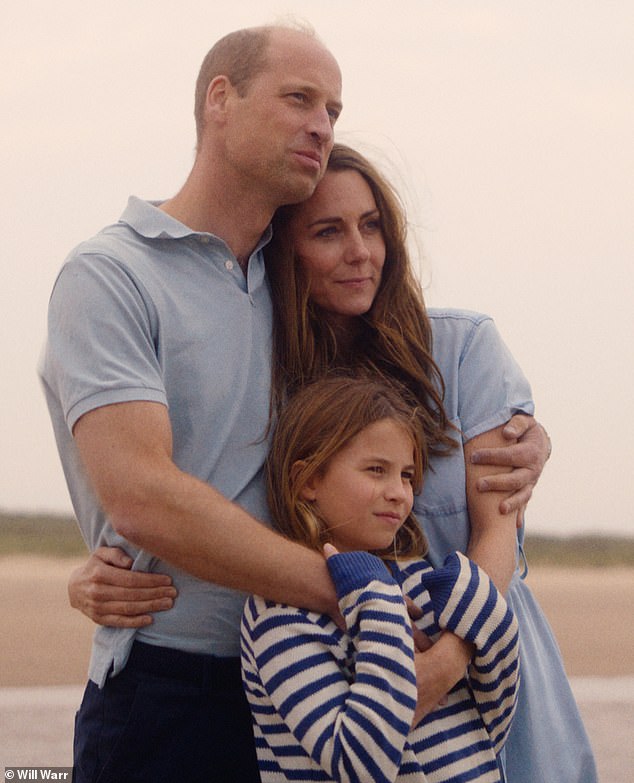 Princess Charlotte hugs her parents as they look out over a beach in Norfolk