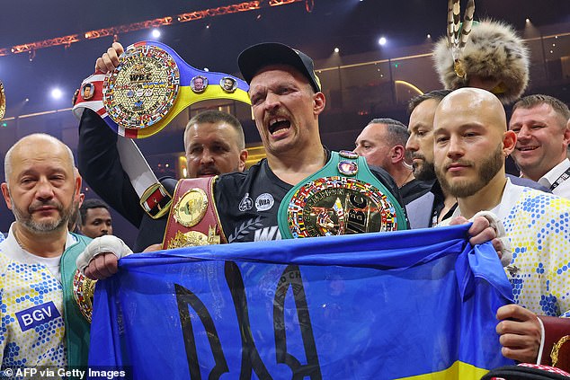 Usyk and his team were emotional after the fight and posed with a Ukrainian flag (above)