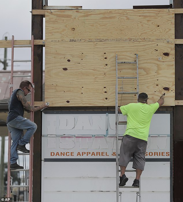 James C. McKenzie (left) and Kelly Blanchard (right) cover an electronic board with plywood in Chalmette, Louisiana on Monday.