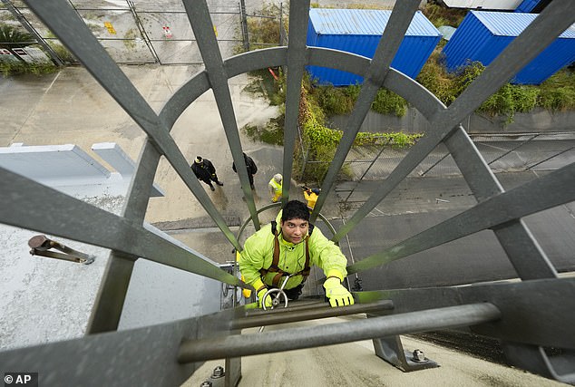 Delwyn Bodden, an employee of the Southeast Louisiana Flood Protection Authority-West, climbs a ladder up a floodgate to close it along the Harvey Canal just outside the New Orleans city limits in Harvey, Louisiana on Tuesday.