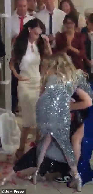 After she finally throws the flowers behind her, three women try to grab the bouquet at the same time - causing chaos