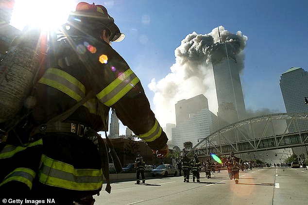 Firefighters walk to one of the World Trade Center towers before it collapsed