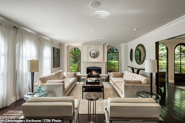 A huge living room is flooded with sunlight as it has patio doors leading outside