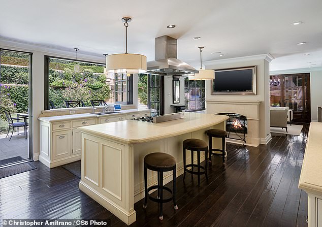 A chef's kitchen features state-of-the-art appliances with built-in features and a wall-mounted window that borders the exterior of the home