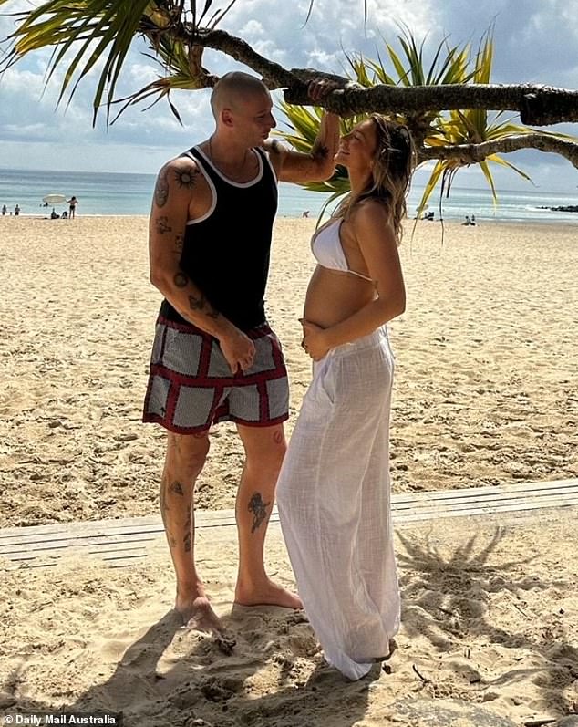 In one photo, Daisy flashed a wide smile as she looked lovingly at Example, who stood next to her on the beach wearing a black tank top and red board shorts