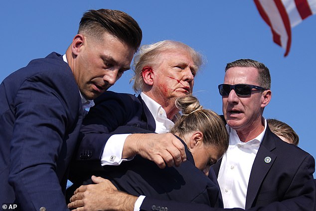 Republican presidential candidate and former President Donald Trump gestures as he is surrounded by U.S. Secret Service agents during a campaign rally, Saturday, July 13, 2024, in Butler, Pennsylvania