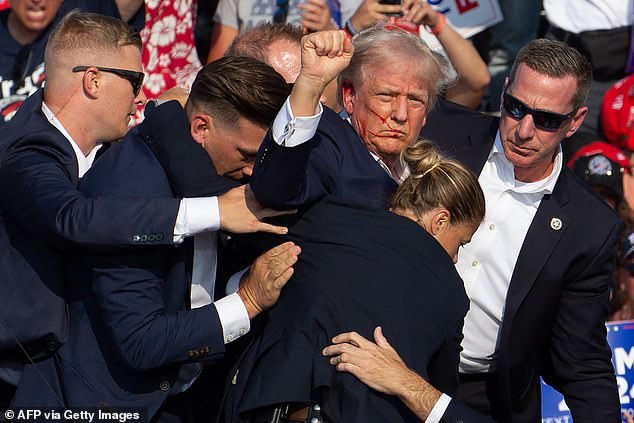 US Republican candidate Donald Trump is surrounded by Secret Service agents with blood on his face as he is escorted off stage at a campaign rally in Butler